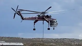 White & red sky crane helicopter flying in from a distance to come in for landing at the airport