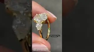 2ct oval trilogy ring with 0.28ct pear cut sides and 2 emerald stones on each side of the engraving