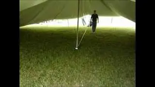 Raising the center pole of a large tent.