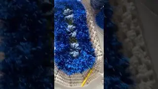 Овальный вязаный коврик с квадратным узором в виде цветка-вертушки и основанием, выполненным из п...