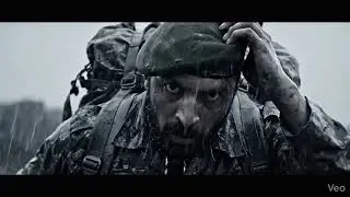 Pakistani army soldie walking through heavy rain and mud, carrying a heavy backpack. His uniform