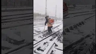 Employees removing snow from railway tracks to allow train passage