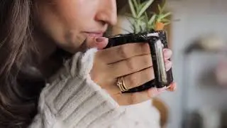 A Cup of Tea with Rosemary, Cinnamon Stick, Lemon Slices, and a Person Slicing an Orange