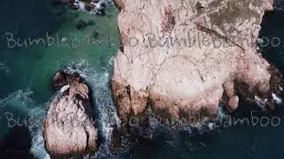 Aerial top view of waves break on rocks in a blue ocean. Stock footage. Sea waves on beautiful beach