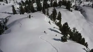Aerial tracking shot of a snowboarder riding down a backcountry mountain in the Sea to Sky area.