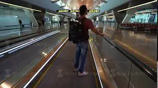 man passing on flat escalator at airport terminal, passenger looking around excited, travel concept