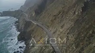 Following Highway 1, coastal cliffs, tilt down tracking a white car, Big Sur, Califo.. | DFKSF03_112