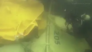 Группа водолазов ВМС США оказывает помощь в подъеме вертолета, сбросившего бомбу.