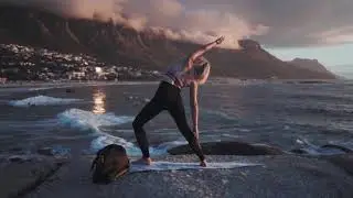 Woman Meditating In Yoga Warrior Pose At The Ocean, Beach  And Rock Mountains.