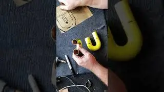 Hand making a bass sax crook.