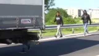 Migrants attempt to climb onto trucks