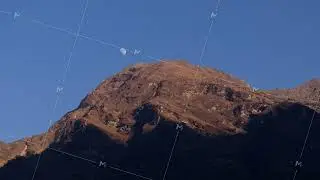 Himalayan mountain peak towering under moonset, casting dramatic silhouette against azure sky with