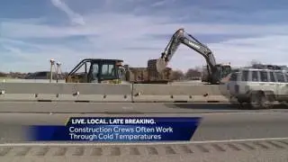 Construction workers try to keep warm as freezing weather moves in