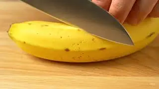 Person Slicing a Banana Lengthwise on a Cutting Board
