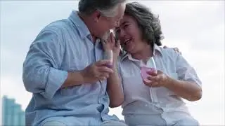 Asian senior couple drinking beverages and relaxing on the beach