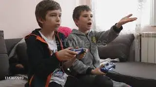 Little gamers - 4K stock videoTwo cheerful boys having fun in video games at home