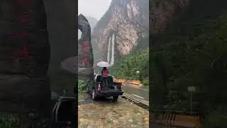 Wow, that's a clever way to keep the umbrella dry! 🌂🚗 Love the waterfall view too! #nature#waterfall
