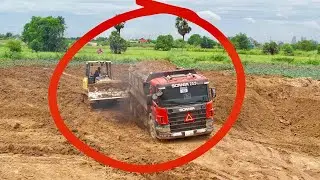 Bulldozer Pushing Dump Truck Stuck on Sticky Soil
