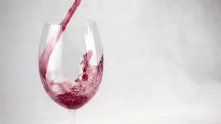 Wine glass close-up. In a glass of wine poured in slow motion