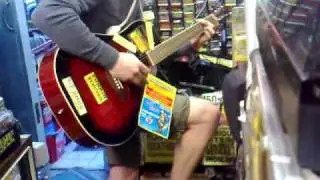 Unknown guitarist jams on accoustic electric Guitar at Backtracks music shop Edinburgh UK