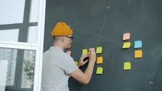 Creative entrepreneur busy with office work writing on colorful sticky notes on chalk board