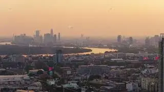 Aerial view of Bangkok's urban skyline with the Chao Phraya River reflecting warm glow of sunset