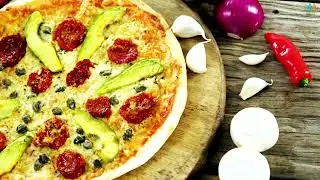 Gourmet pizza slice with avocado sun dried tomatoes and capers on rustic wooden table with cherry