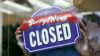 Female Store Owner Wearing A Face Mask Reluctantly Turns Her Shop Sign To Closed.