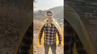 Man puts on a bright, shimmering cape and strikes a heroic pose.