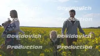 A happy family walks on a rapeseed field.