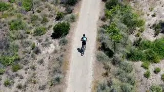 Aerial view of mountain biker riding in a dusty mountain trail | 4K Free Stock Video