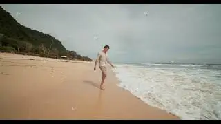 Young attractive man walking on the wet sand into the ocean swell in the beach in Uluwatu, Bali and