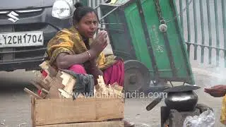 Woman cooks food on a roadside in Delhi: Desperation of poverty in winter-time north India