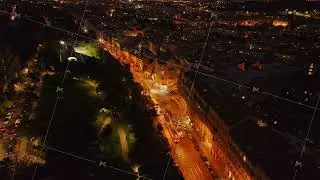 Aerial views showcase trams moving along a road next to a park at night in Prague, Czech Republic