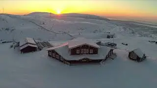 aerial shot of wooden houses in snowfields ski centre on the north winter scene with hills and golde