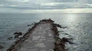 Wide Angle View Of Stone Jetty Extending Into Ocean Under Overcast Sky Video