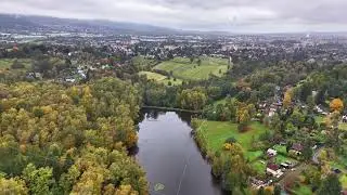 vivid autumn scene from above, overcast sky complements colorful trees surrounding peaceful