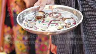 Woman holding sacred puja thali with offerings during Indian religious ritual