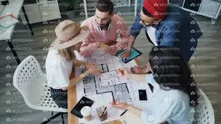 High angle view of interior designers discussing design looking at building plan