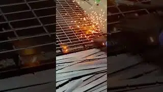Skilled worker welding steel grating with bright sparks illuminating the industrial workspace