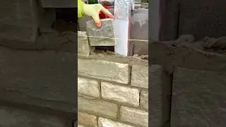 Careful Placement of Textured Stone Blocks by a Worker During Wall Cladding Installation