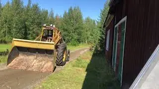 Tractor grading a forest road leading to a special house for a friend mid Arctic summer.
