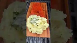 Sweet & Spicy Cedar Plank Salmon With Cedar Smoked Mashed Potatoes grilled on coals.