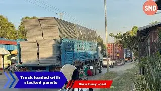 Truck loaded with stacked panels on a busy road