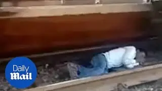 Shocking moment man lays down under a moving TRAIN!