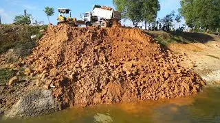 Massive Earthmoving Operation: Bulldozer & Dump Truck Filling Pond with Rock & Dirt.