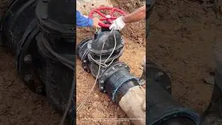 Collaboration on the construction site: excavator + workers, precise installation of valves