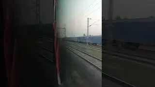 Twin GE diesel locomotives standing in loop line with a long freight train