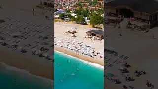 Vertical video. Oludeniz, Turkey. Aerial view of busy Oludeniz Beach, tourists at waterfront cafe...