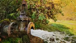 Old rusty part of water well and system of disposal with strong aqua stream pouring from it